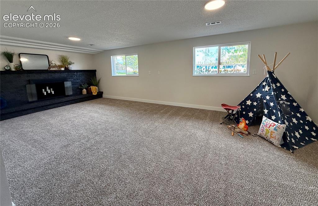 Image 19 of 25: Large garden level rec room with wood burning fireplace