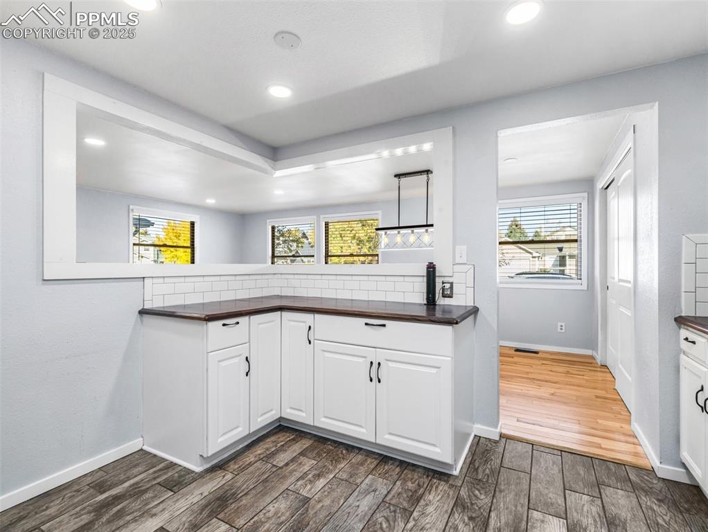 Image 12 of 29: Kitchen with white cabinetry, dark wood finished floors, healthy amount of 