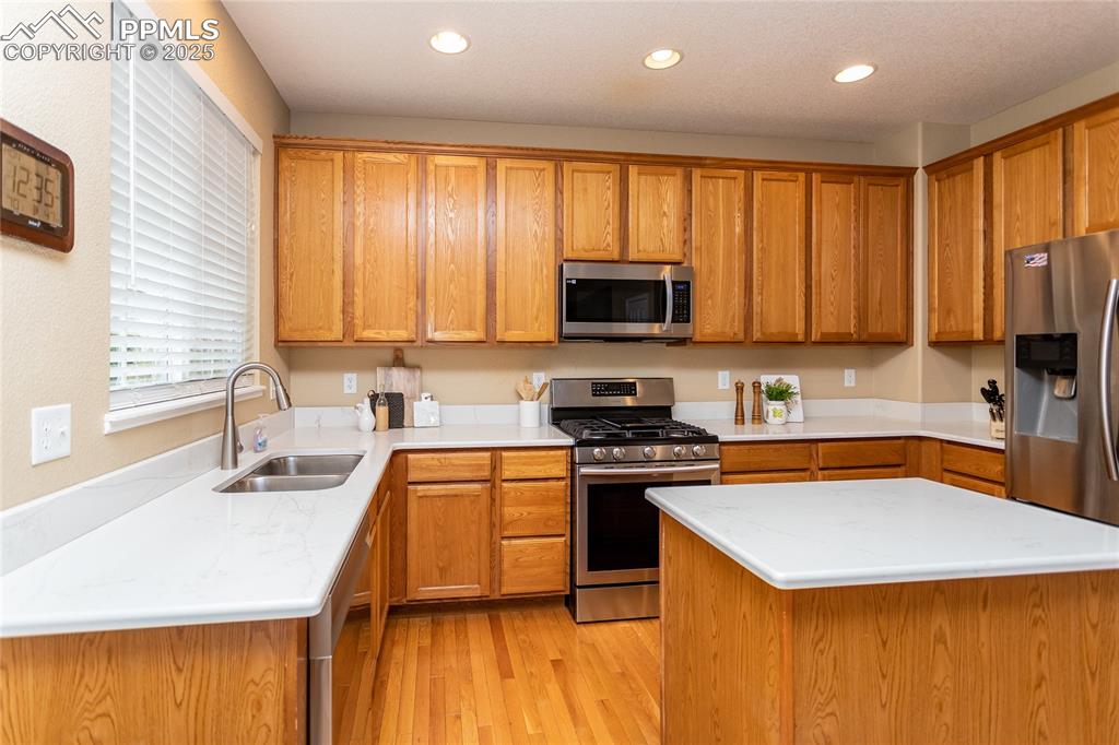 Image 10 of 40: Kitchen with stainless steel appliances, a sink, light wood-style flooring,