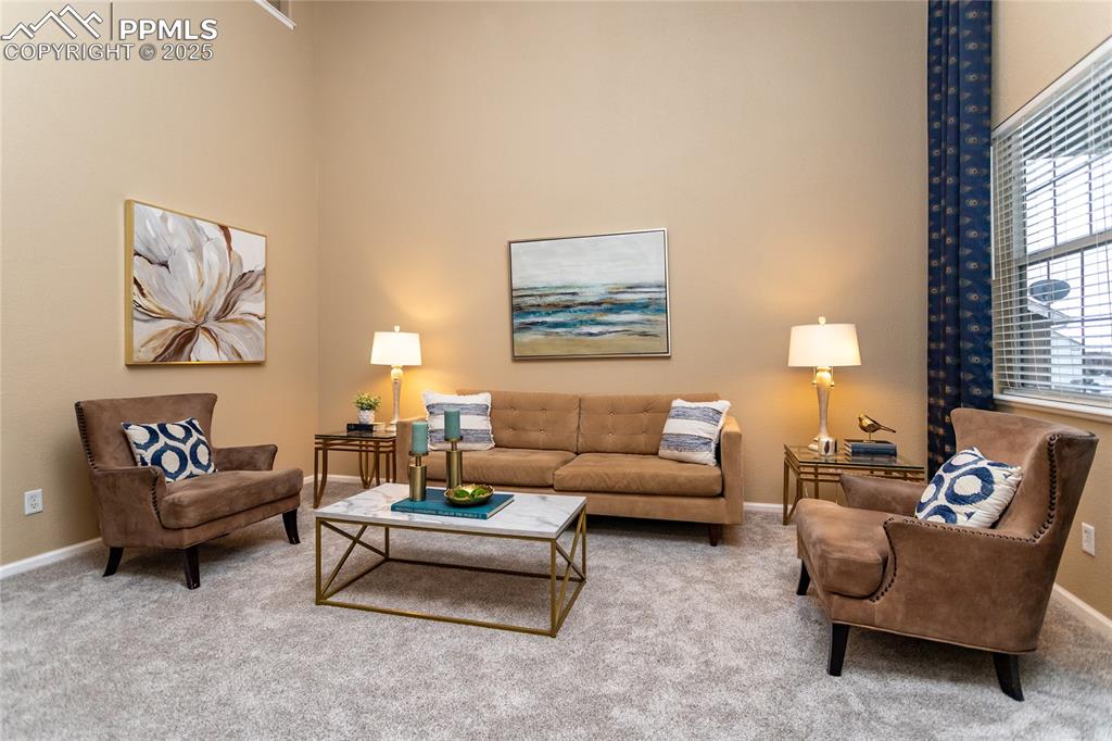Image 17 of 40: Carpeted living room with a towering ceiling and baseboards