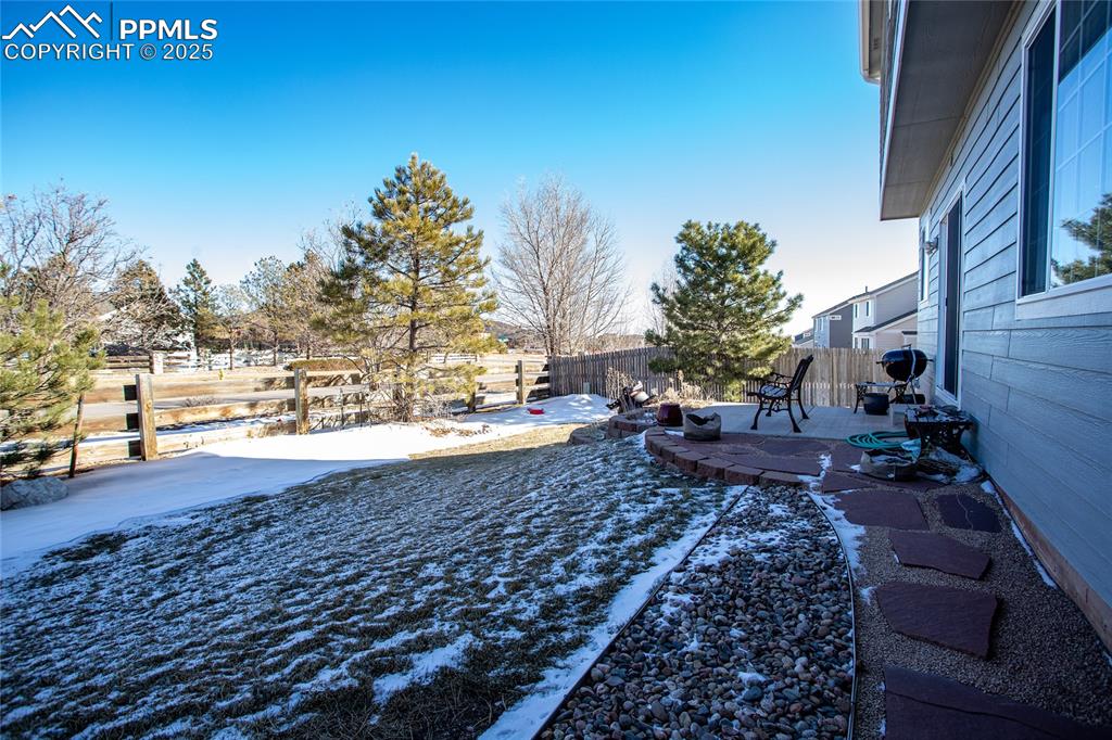 Image 38 of 40: Yard layered in snow with a patio area and a fenced backyard