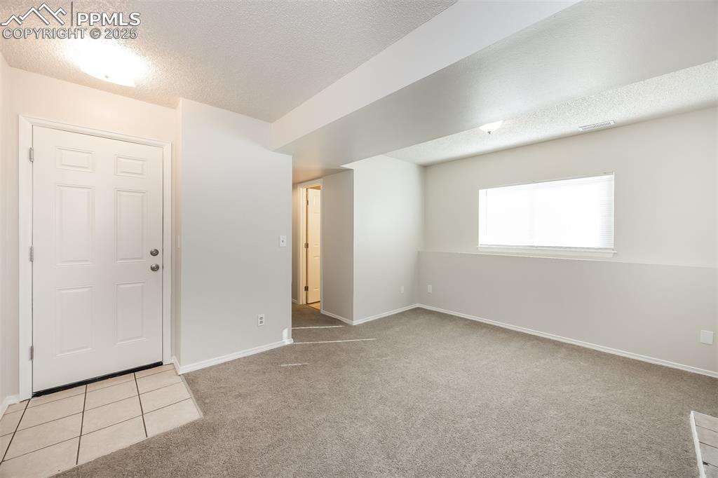 Image 12 of 25: Spare room featuring a textured ceiling, light colored carpet, and baseboar