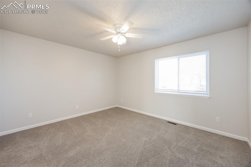 Image 14 of 25: Carpeted empty room with ceiling fan, baseboards, and a textured ceiling
