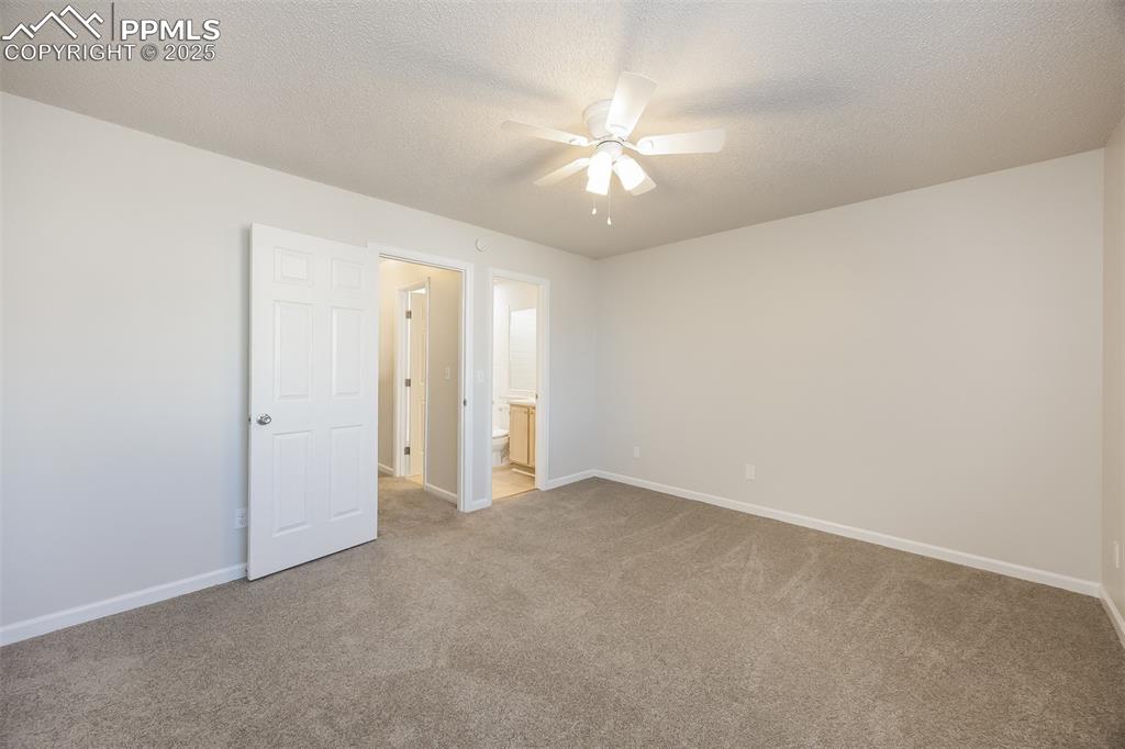 Image 15 of 25: Spare room featuring ceiling fan, carpet floors, baseboards, and a textured