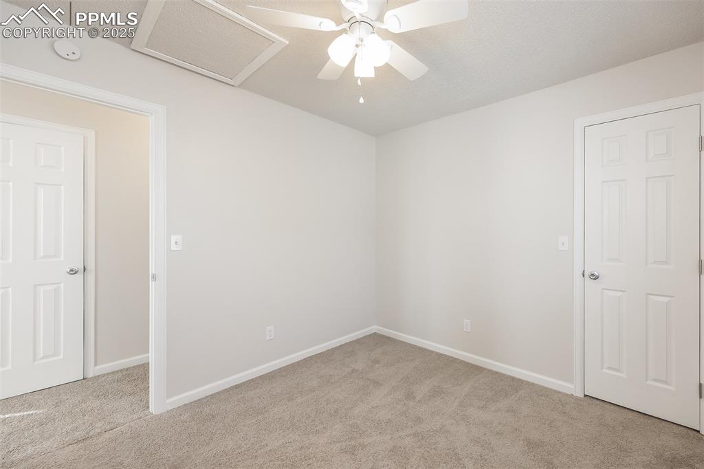Image 17 of 25: Carpeted empty room featuring attic access, baseboards, ceiling fan, and a 
