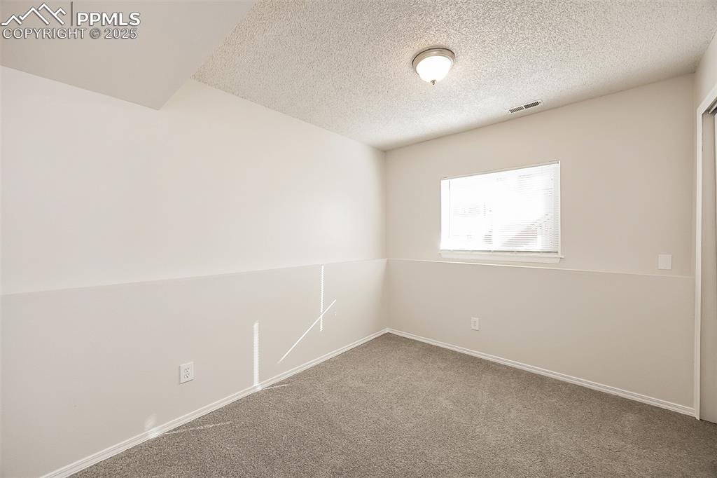 Image 18 of 25: Spare room featuring carpet, a textured ceiling, and baseboards