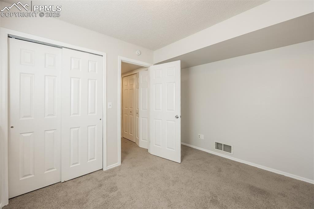 Image 20 of 25: Unfurnished bedroom with carpet floors, baseboards, a closet, and a texture