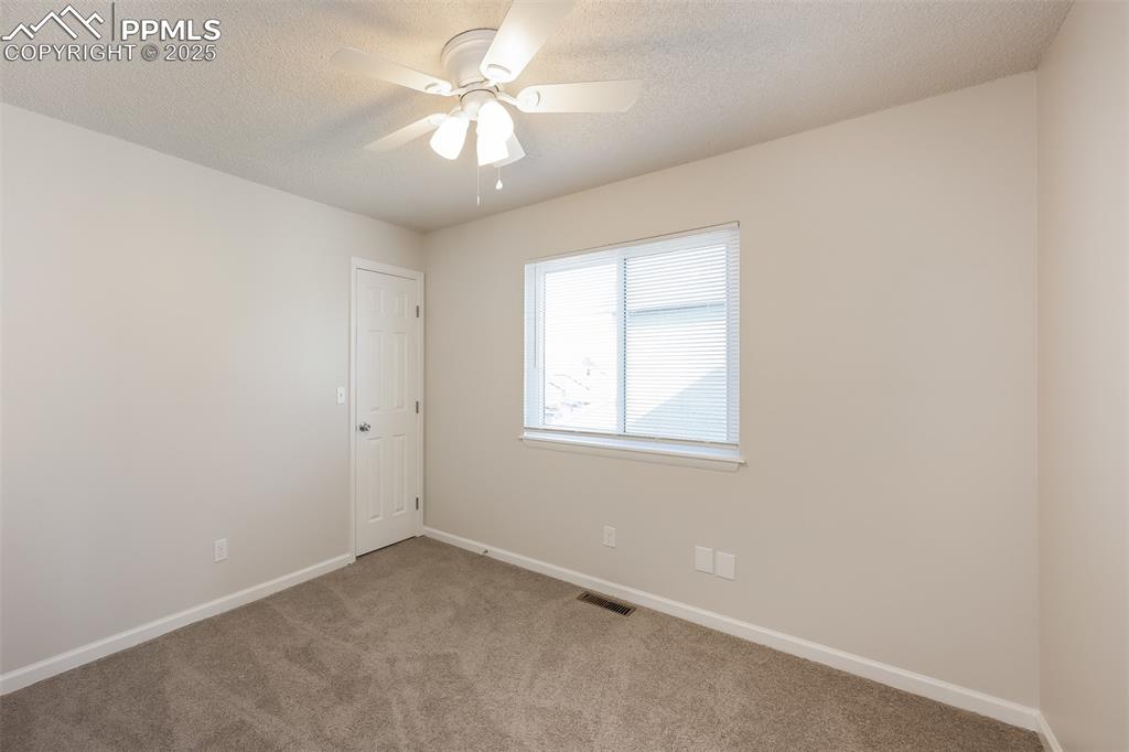 Image 21 of 25: Empty room with carpet floors, ceiling fan, baseboards, and a textured ceil