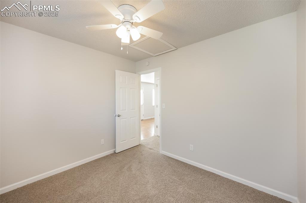 Image 22 of 25: Empty room with light colored carpet, ceiling fan, and baseboards