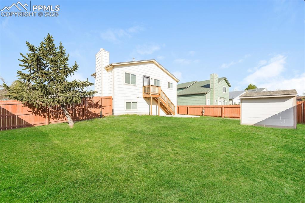 Image 25 of 25: Back of property with stairway, a chimney, an outdoor structure, and a stor