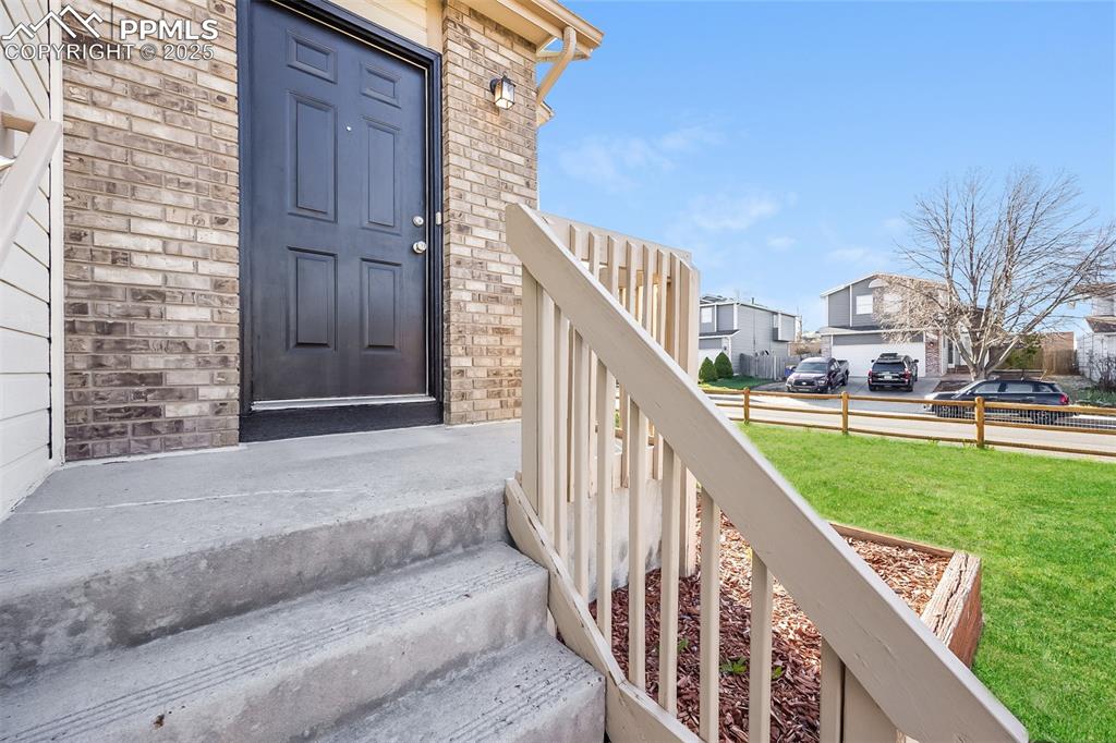 Image 3 of 25: Entrance to property featuring a lawn, a residential view, and brick siding