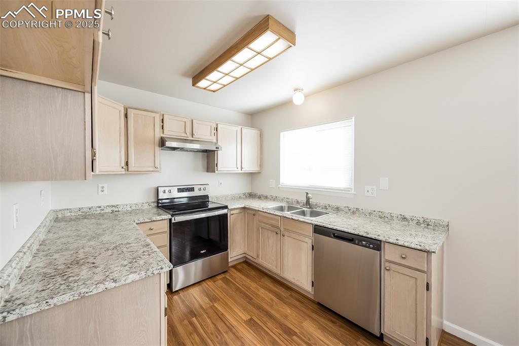Image 8 of 25: Kitchen featuring stainless steel appliances, a sink, wood finished floors,
