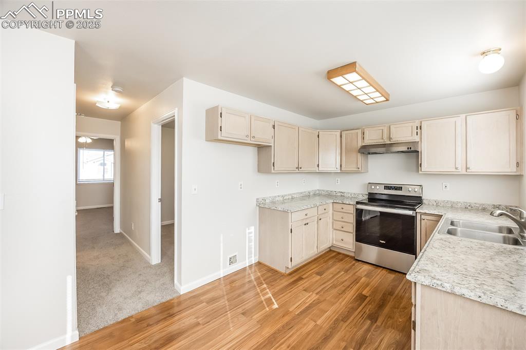 Image 9 of 25: Kitchen featuring stainless steel electric stove, a sink, light wood finish
