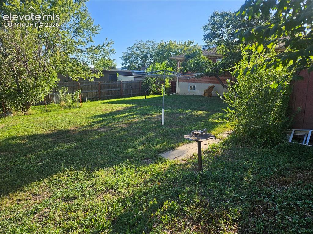 Image 36 of 37: Expansive yard with privacy fence and some mature trees