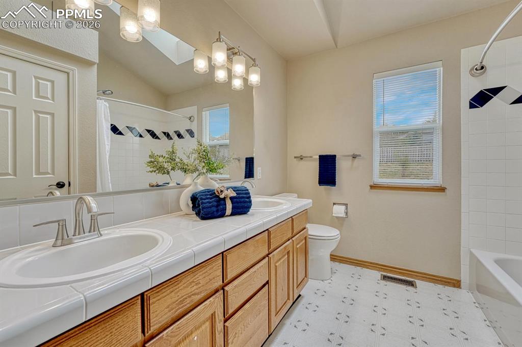 Image 26 of 47: Large secondary full bathroom on upper level with dual vanities and linen c