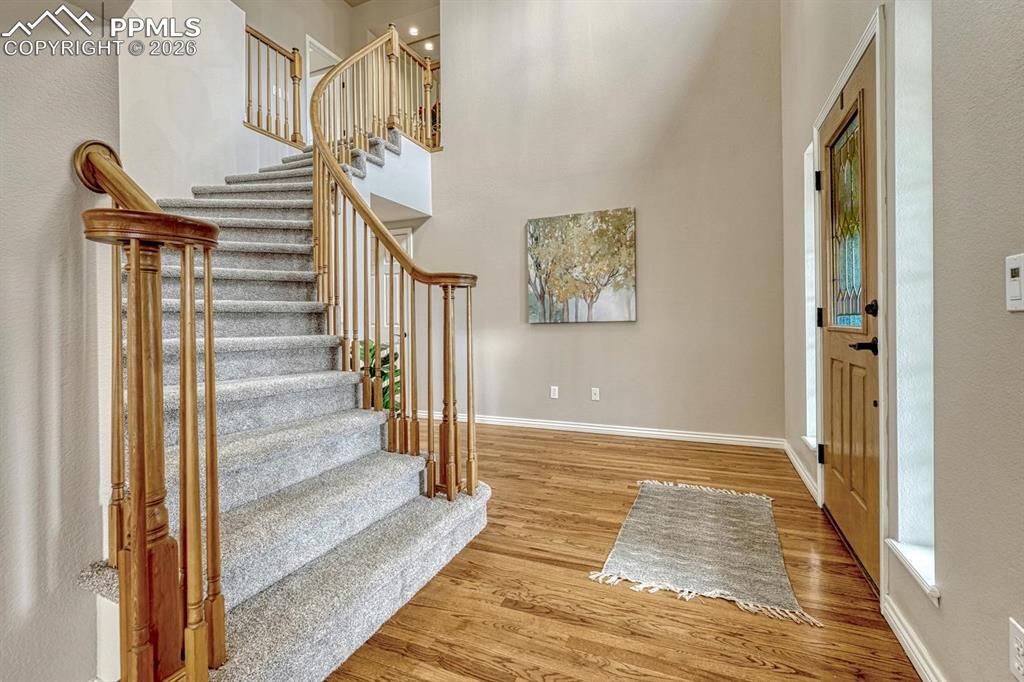 Image 4 of 47: Grand foyer with spiral staircase and hardwood.