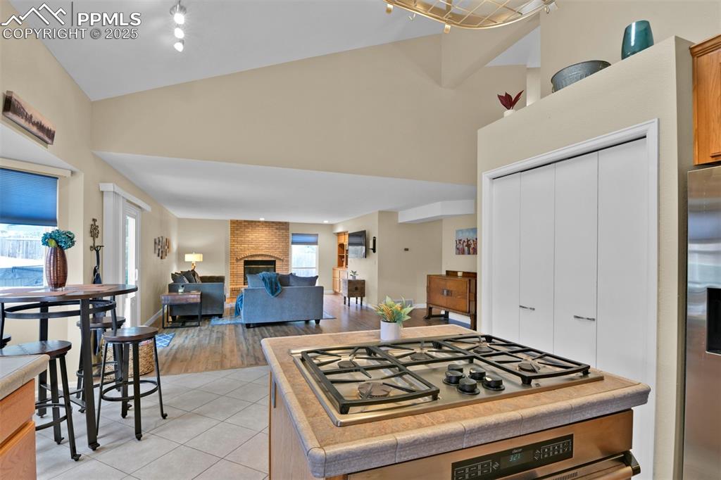 Image 14 of 50: Kitchen with appliances with stainless steel finishes, a brick fireplace, l