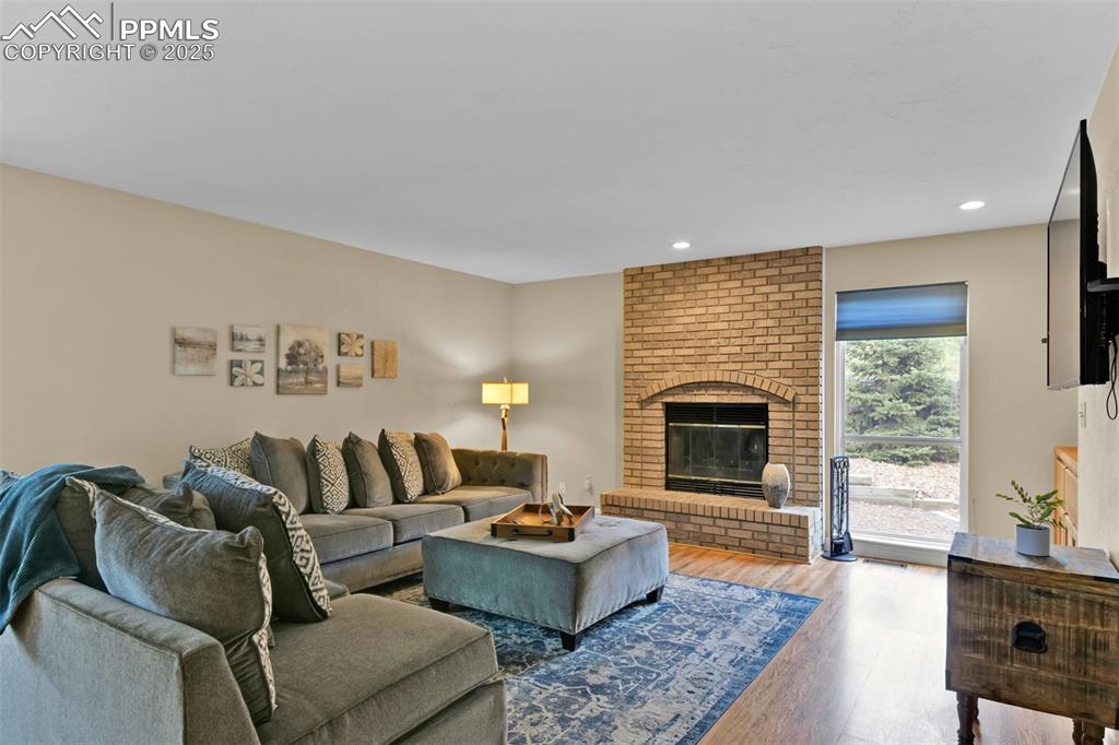 Image 18 of 50: Living area featuring a fireplace, wood finished floors, and recessed light