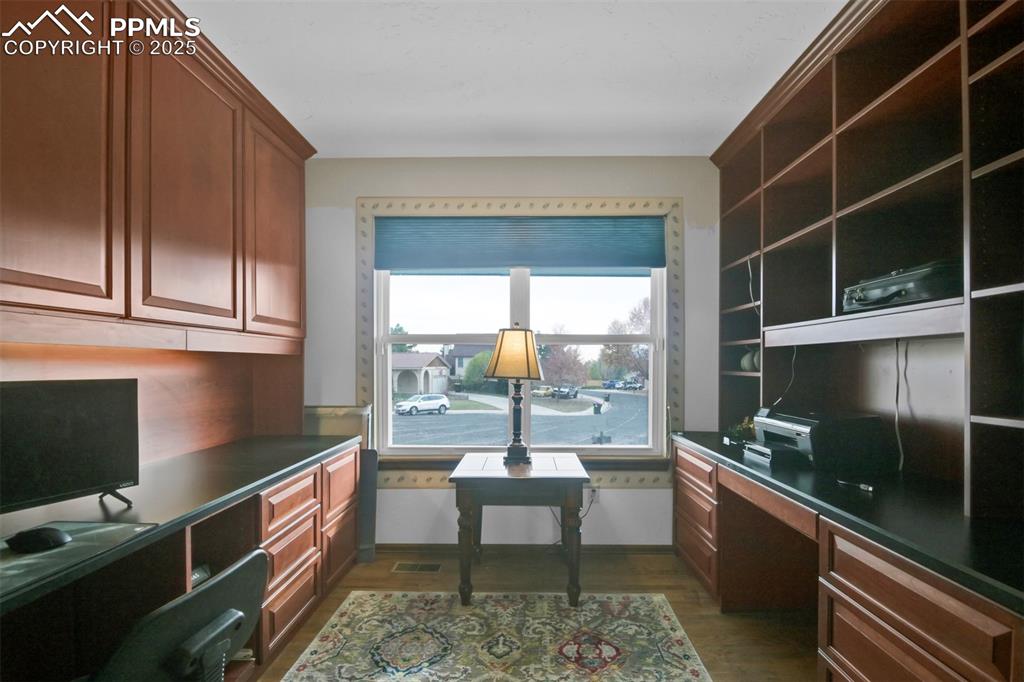 Image 22 of 50: Home office featuring built in desk and dark wood-type flooring