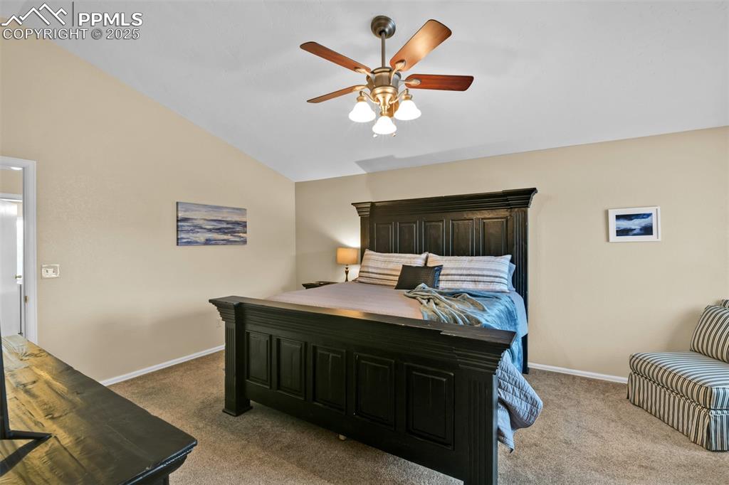 Image 26 of 50: Bedroom with lofted ceiling, light carpet, and ceiling fan