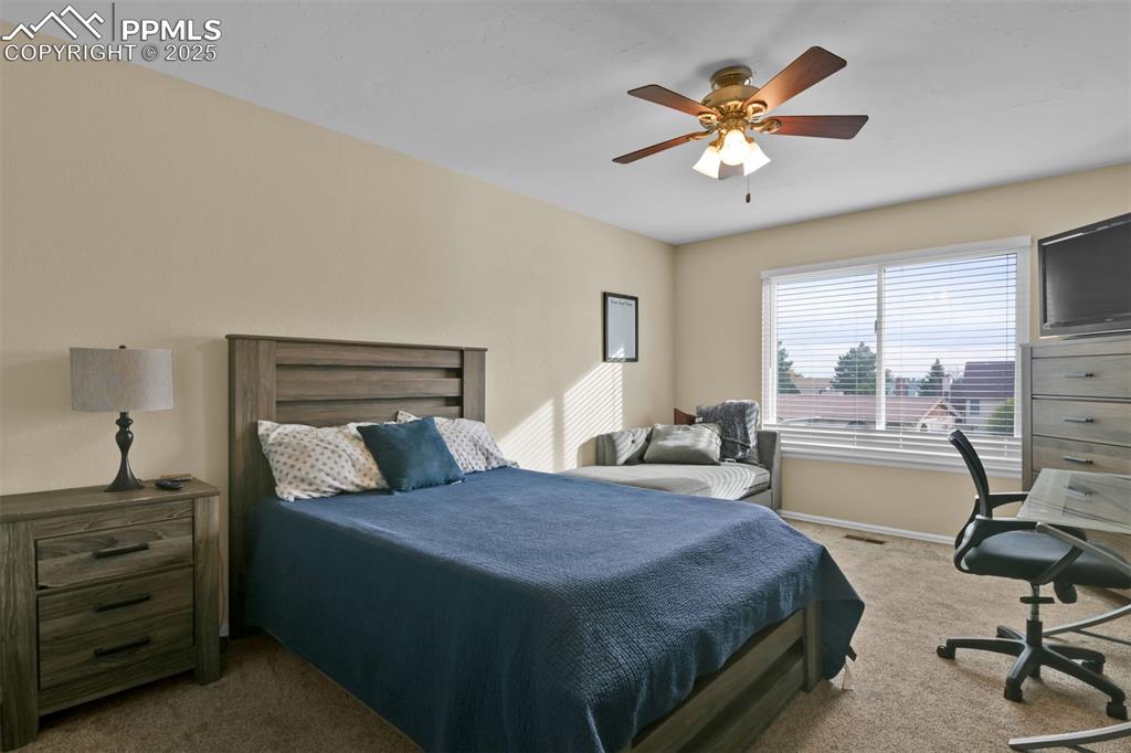Image 31 of 50: Carpeted bedroom featuring ceiling fan and a desk