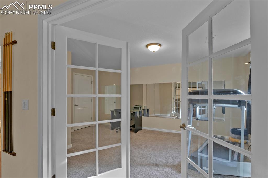 Image 45 of 50: Walk in closet with french doors and light colored carpet