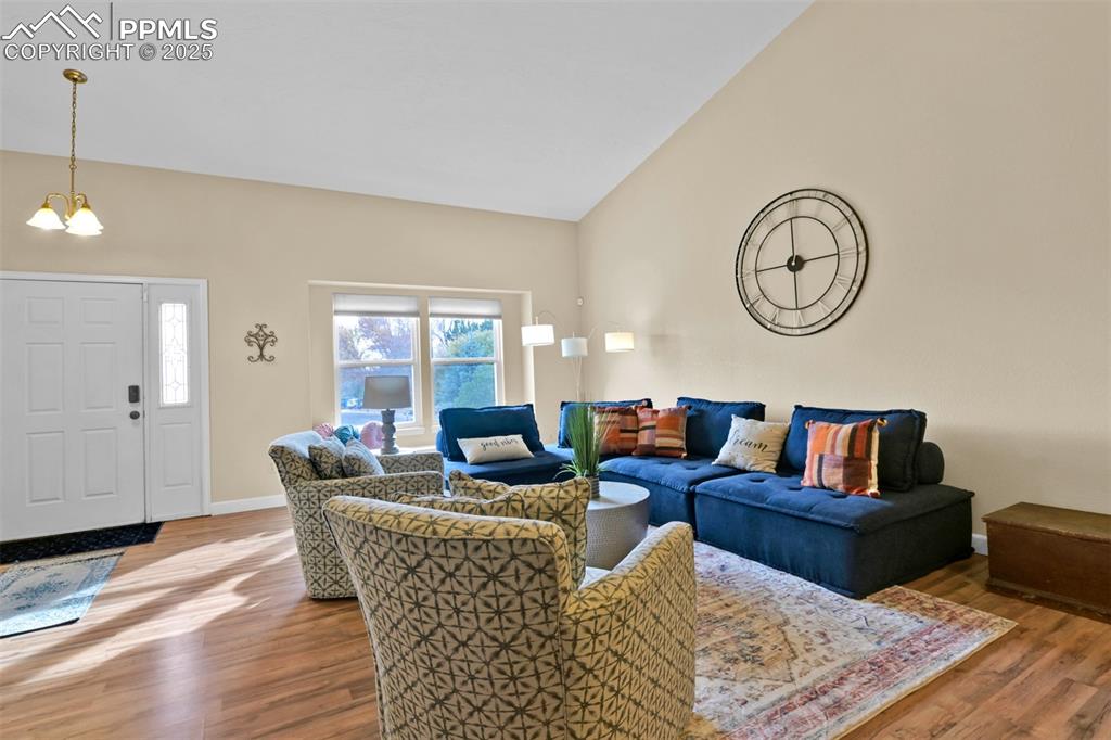 Image 5 of 50: Living area with wood finished floors, a chandelier, and lofted ceiling