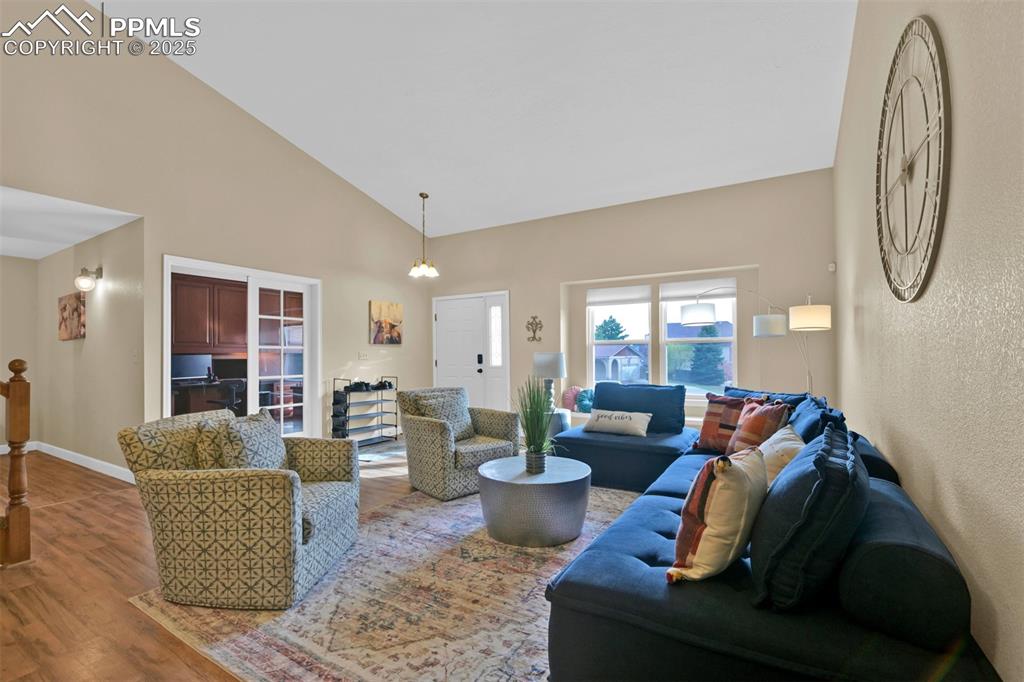 Image 6 of 50: Living area featuring high vaulted ceiling and wood finished floors