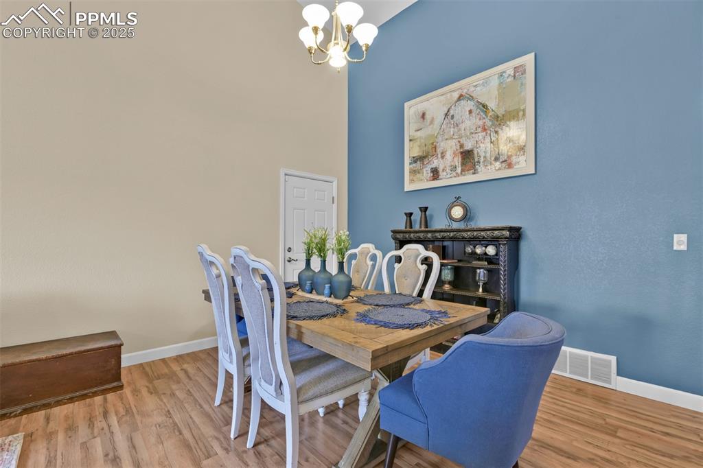 Image 7 of 50: Dining space with a chandelier, wood finished floors, and a high ceiling