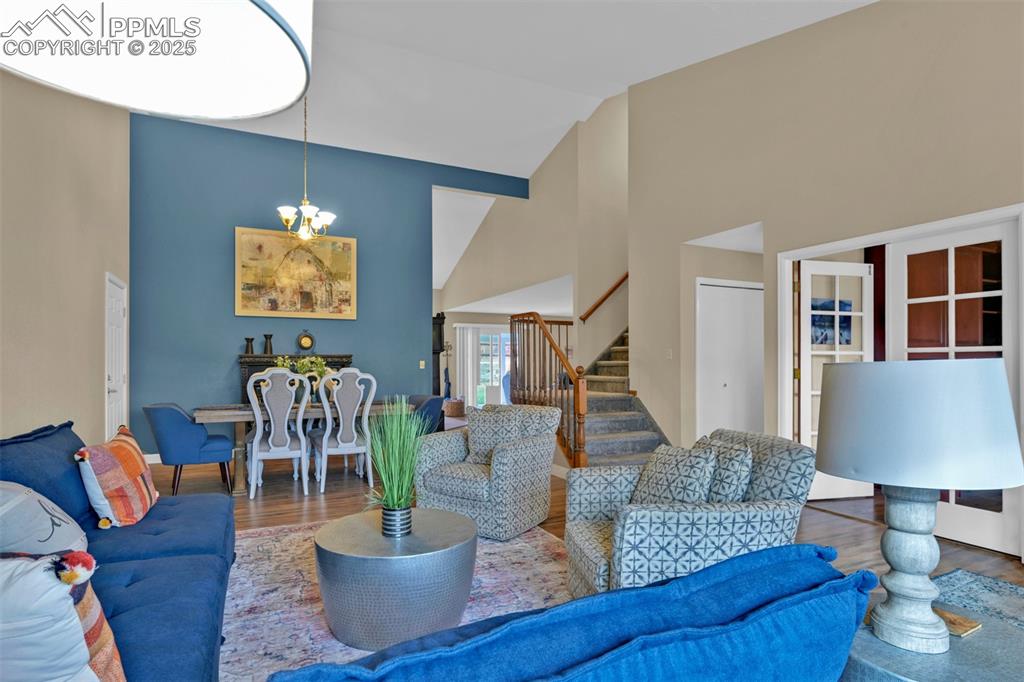 Image 9 of 50: Living area with high vaulted ceiling, wood finished floors, stairway, and