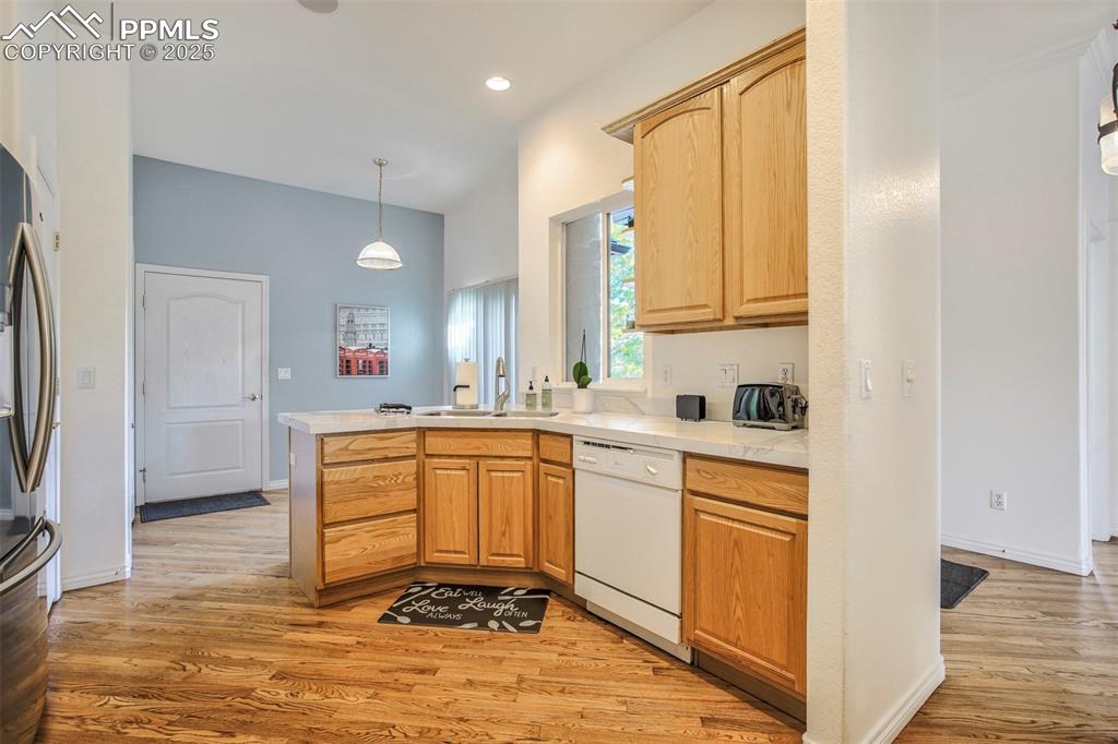 Image 10 of 33: Kitchen featuring a peninsula, white dishwasher, light wood-style flooring,
