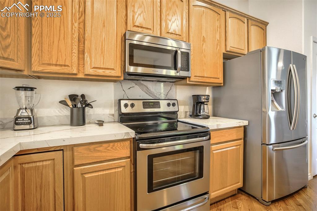 Image 8 of 33: Kitchen featuring stainless steel appliances, decorative backsplash, light