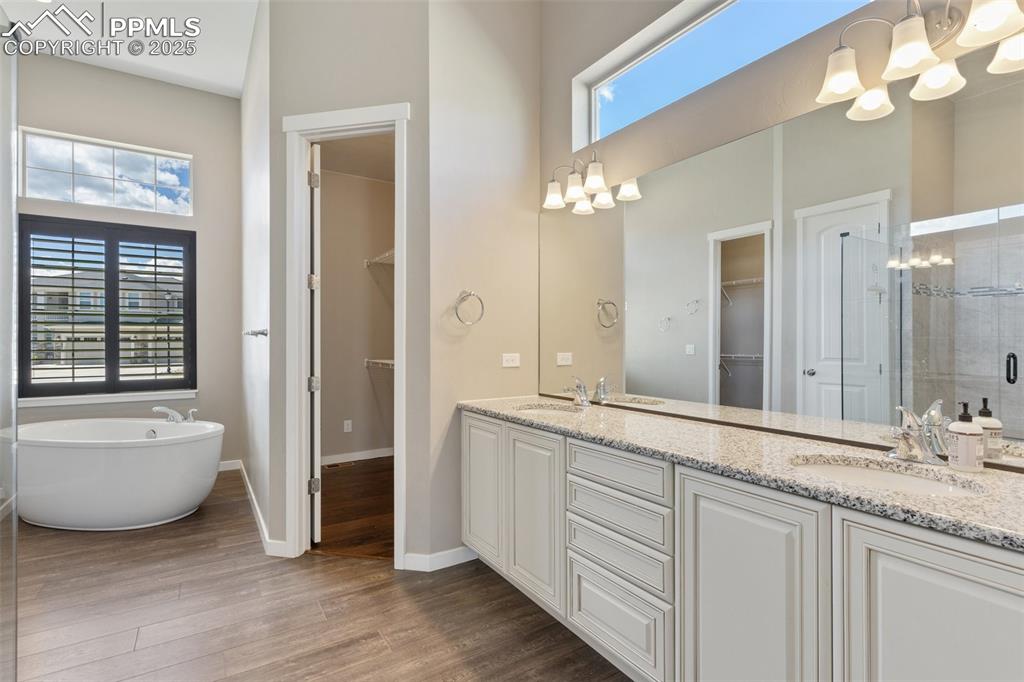Image 15 of 49: Tranquil primary bath oasis with tub situated between double closets, doubl