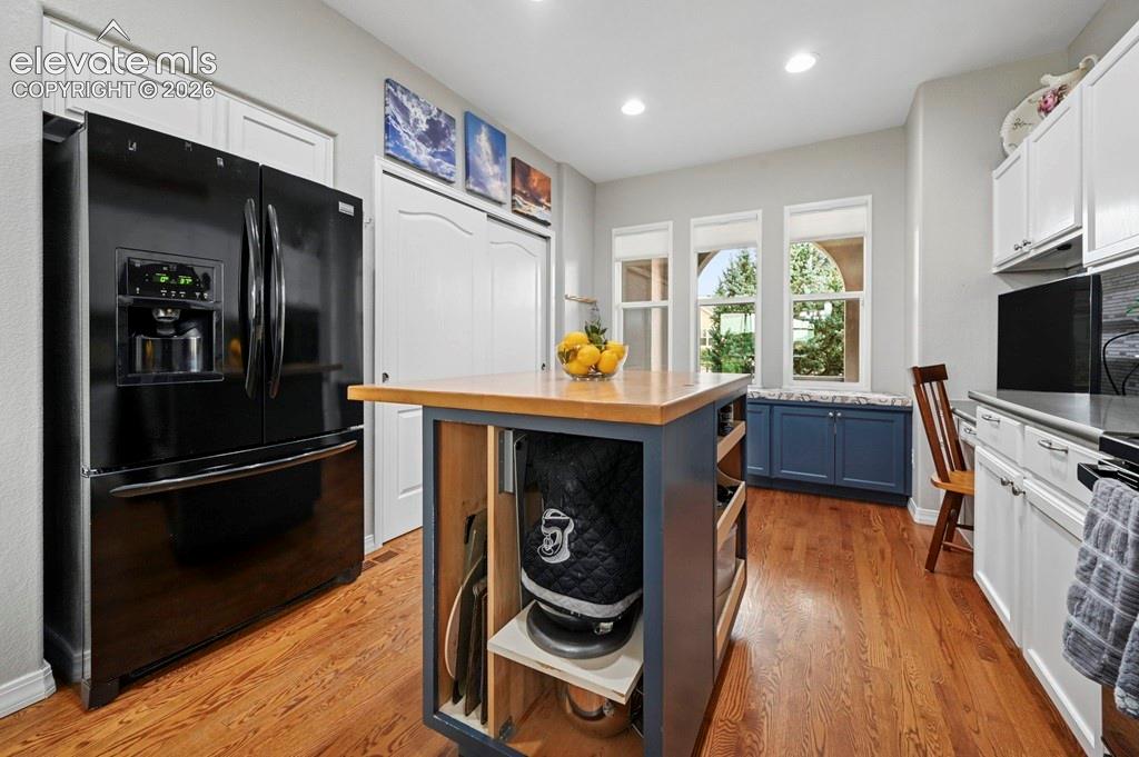 Image 11 of 39: Hardwood flooring, white cabinetry, dark countertop, kitchen island with wo