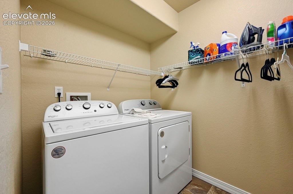 Image 27 of 39: Basement laundry area featuring permanent shelving, a washer, and a dryer