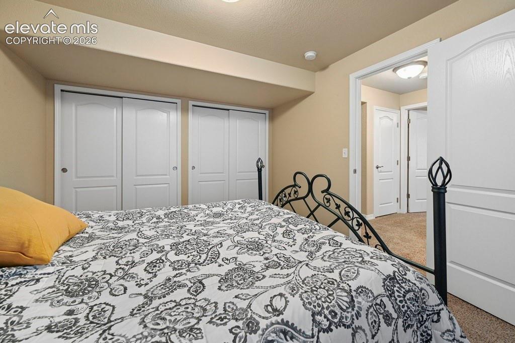 Image 29 of 39: Basement bedroom with Ornamental Metal Bed Frame, Patterned Bedding, Dual C