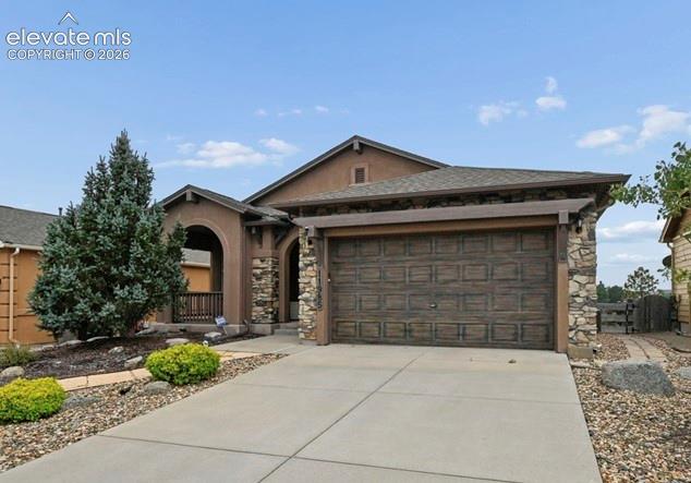 Image 3 of 39: Stucco exterior with stone accents, covered front porch, wood-finish garage