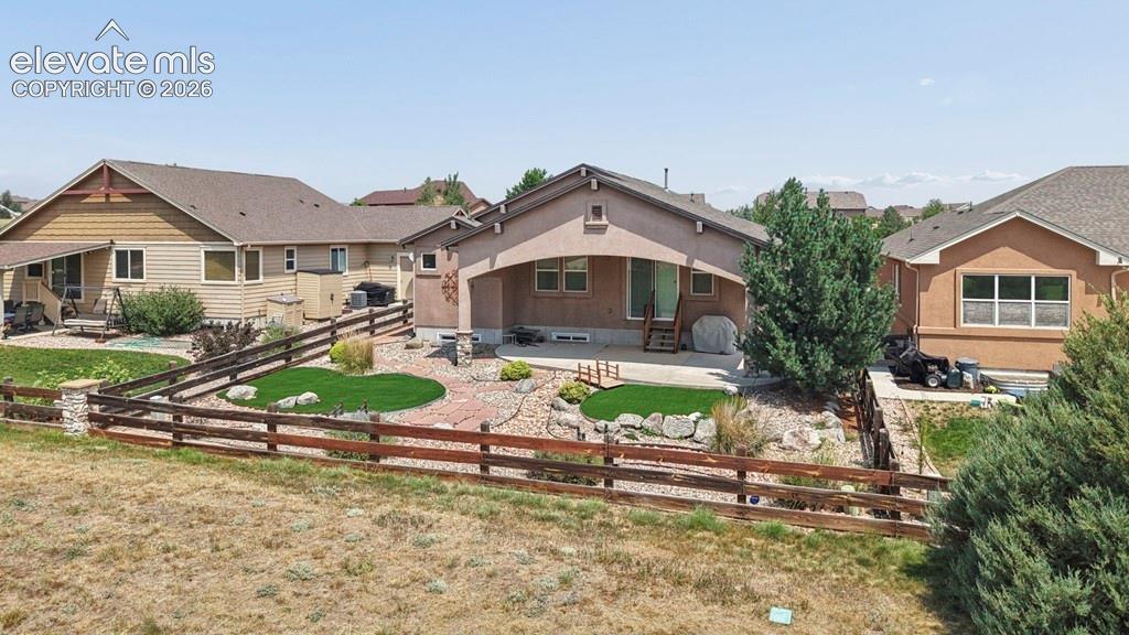 Image 34 of 39: Rear exterior with a covered patio, concrete patio, and a tiered landscaped
