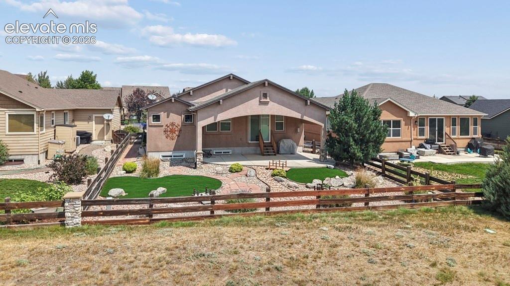 Image 35 of 39: Rear exterior featuring a covered patio, artificial turf, stone patio, and 