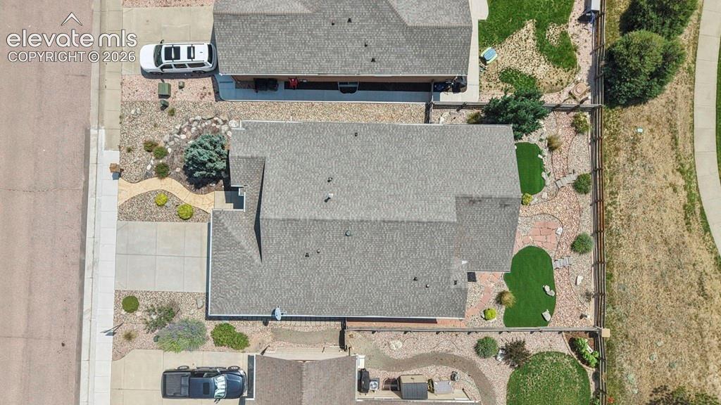 Image 37 of 39: Durable shingle roofing, concrete driveway, and rock landscaping with artif