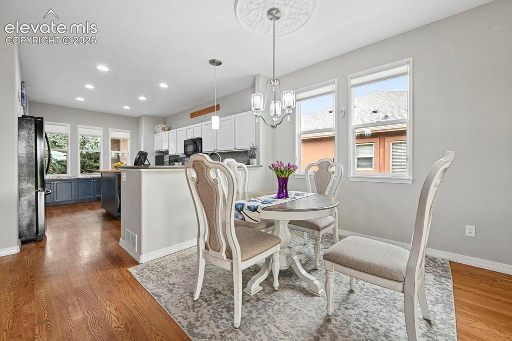 Image 6 of 39: Recessed lighting, wood-finish flooring, white cabinetry, kitchen island wi