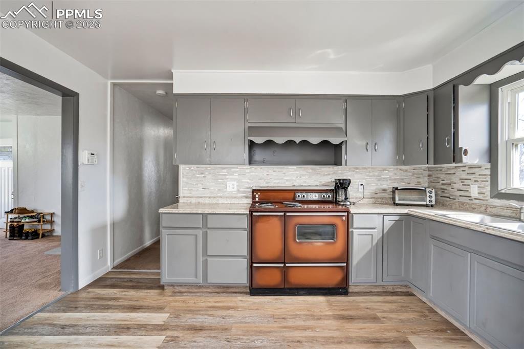 Image 11 of 37: Kitchen, vinyl flooring, stove and countertops, updated backsplash.