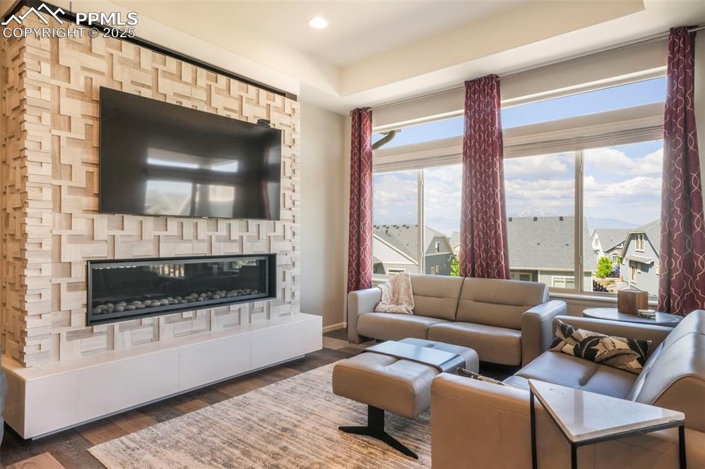 Image 19 of 50: Living room with mountain views, large fireplace, walk out access to deck