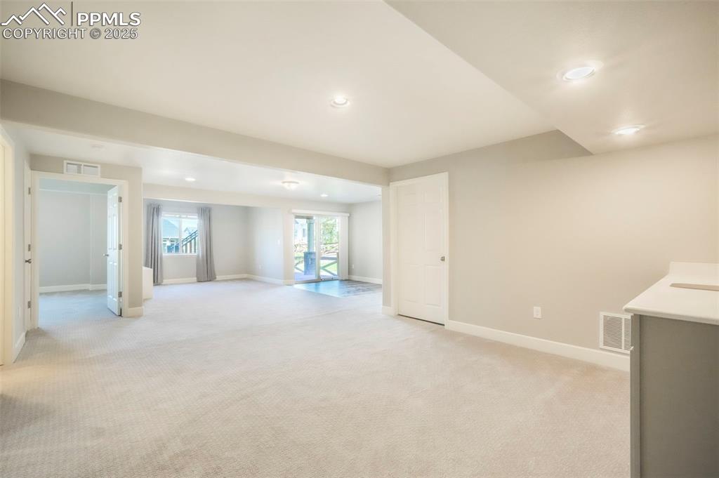 Image 32 of 50: Basement family room with wet bar, walk out access to back patio and landsc