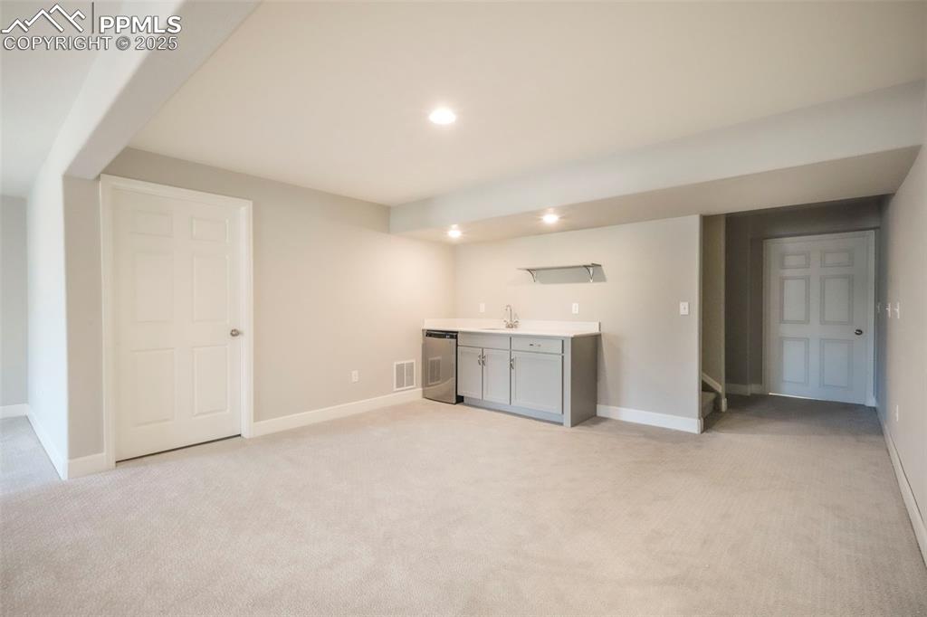Image 33 of 50: Basement family room with wet bar, walk out access to back patio and landsc