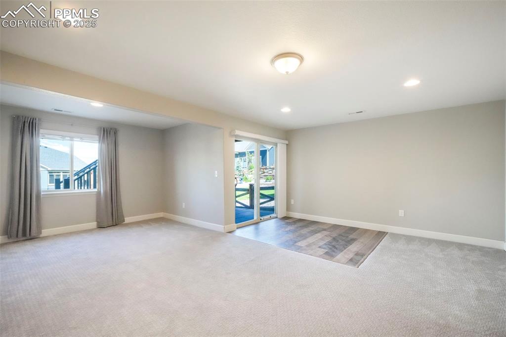 Image 34 of 50: Basement family room with wet bar, walk out access to back patio and landsc