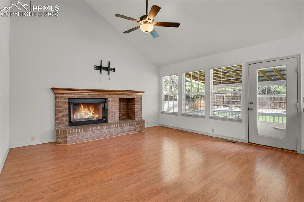 Image 18 of 50: Living area featuring hardwood flooring, a brick fireplace with a wood mant