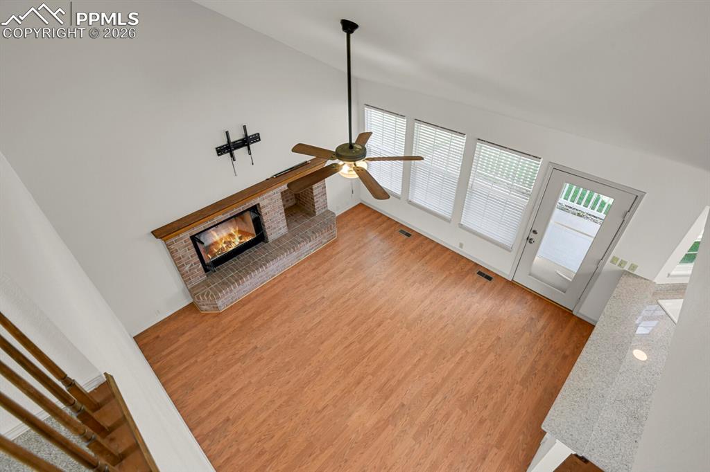 Image 21 of 50: The living area features a brick fireplace, hardwood style flooring, a ceil