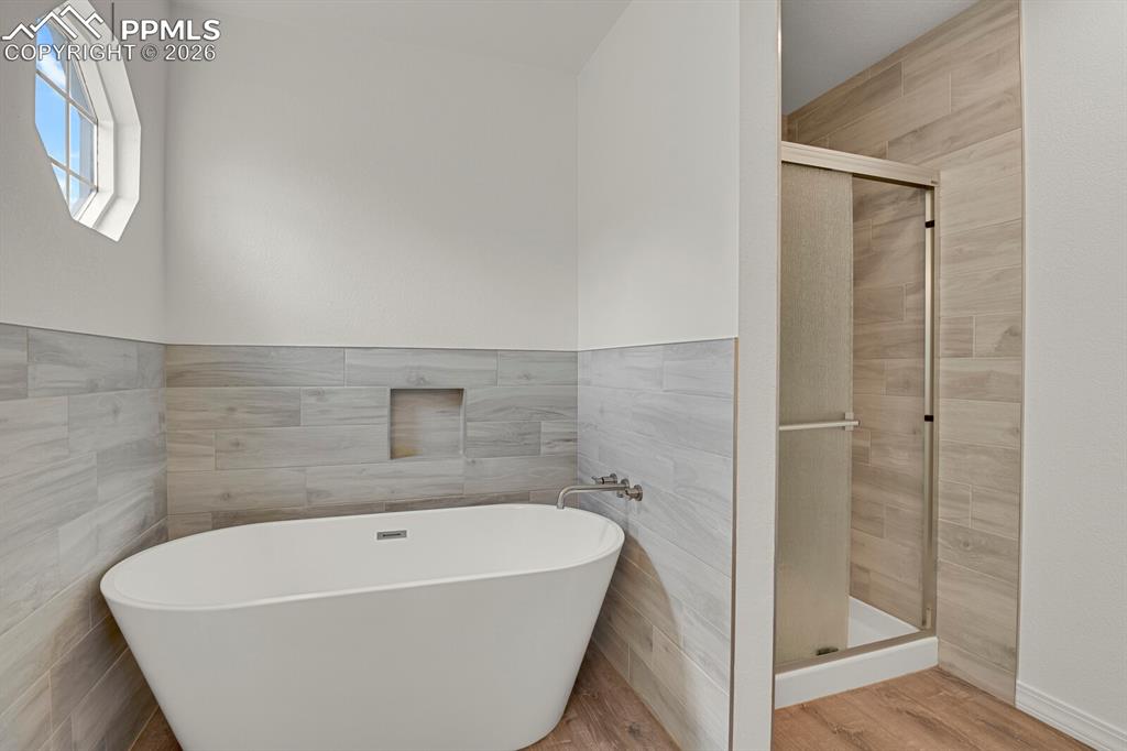 Image 27 of 50: The bathroom features a freestanding soaking tub and a walk-in shower with 