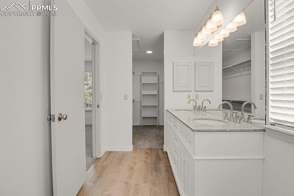 Image 28 of 50: This bathroom features a double vanity with a light-colored granite counter